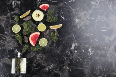 Flat lay composition with bottle of perfume on black marble background, space for text