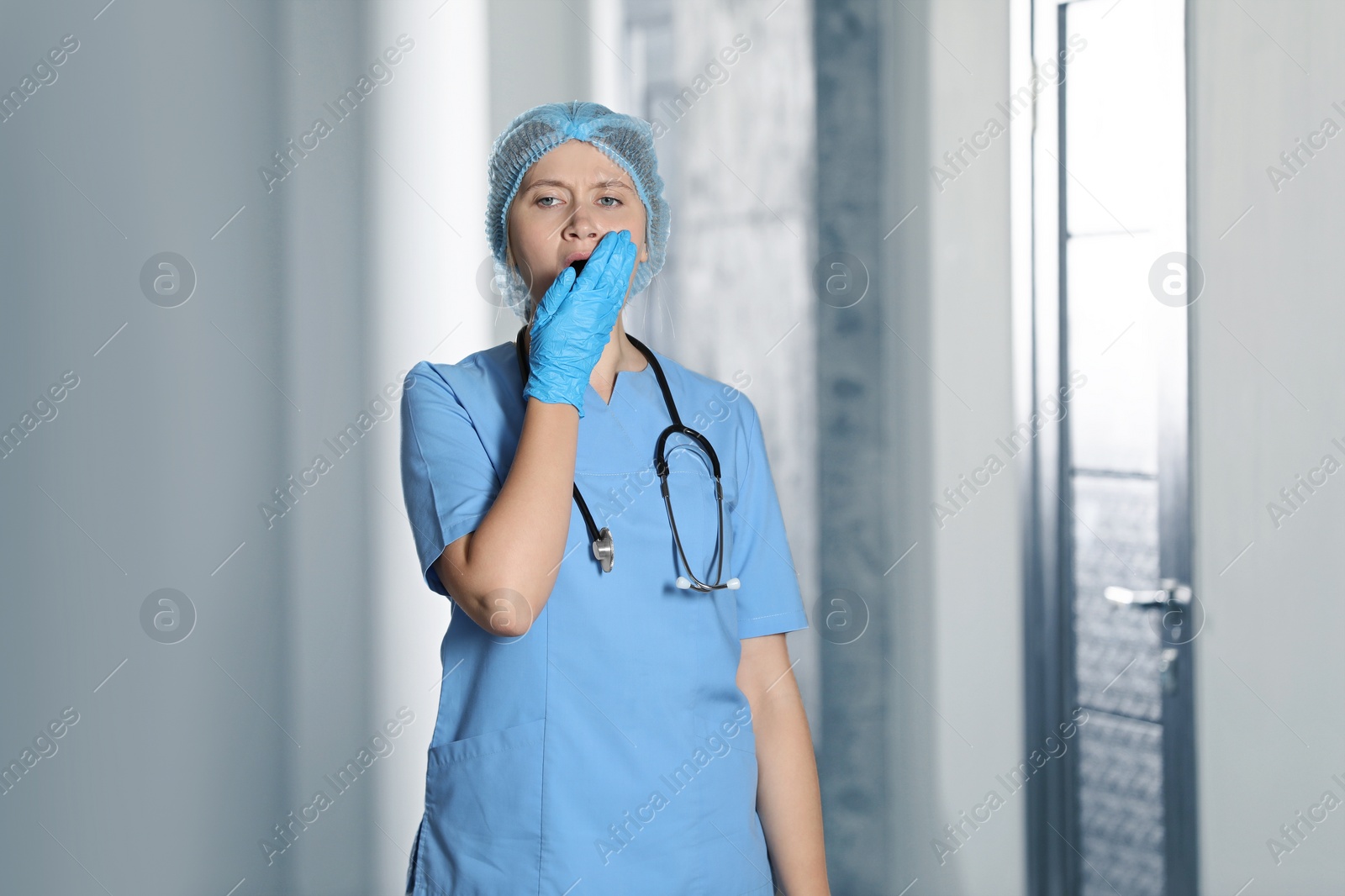 Photo of Exhausted doctor with stethoscope yawning in hospital