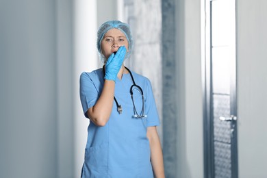 Photo of Exhausted doctor with stethoscope yawning in hospital