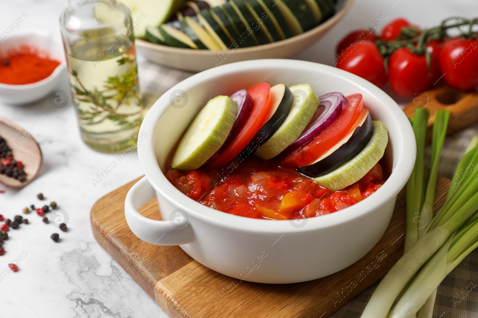 Photo of Dressing for ratatouille with different fresh vegetables on white marble table, closeup