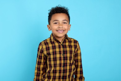 Portrait of cute African-American boy on turquoise background