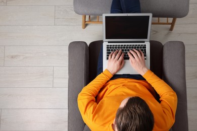 Photo of Man working with laptop in armchair, top view. Space for text