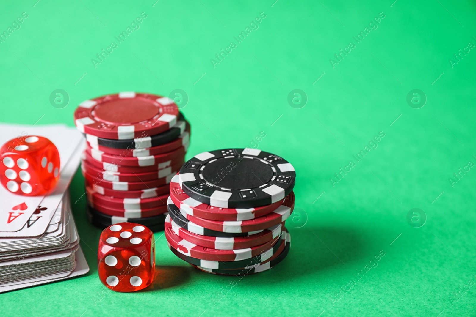 Photo of Poker chips, cards and dices on green background, space for text