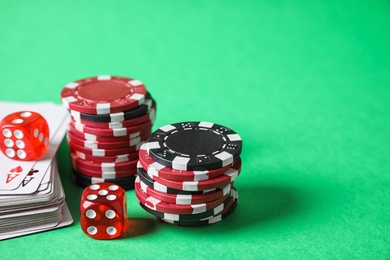 Poker chips, cards and dices on green background, space for text