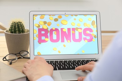 Image of Bonus gaining. Man using laptop at table, closeup. Illustration of falling coins and word on device screen
