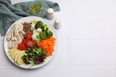 Balanced diet and healthy foods. Plate with different delicious products on white tiled table, top view. Space for text