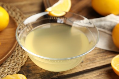 Photo of Freshly squeezed lemon juice in glass bowl on wooden table
