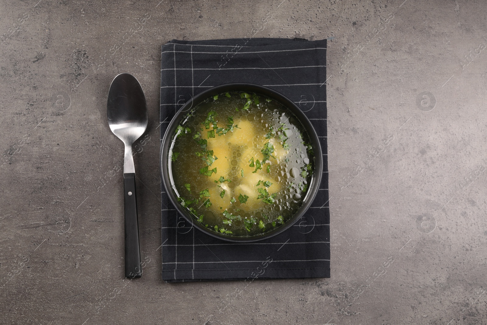 Photo of Delicious chicken soup with parsley and spoon on grey table, flat lay