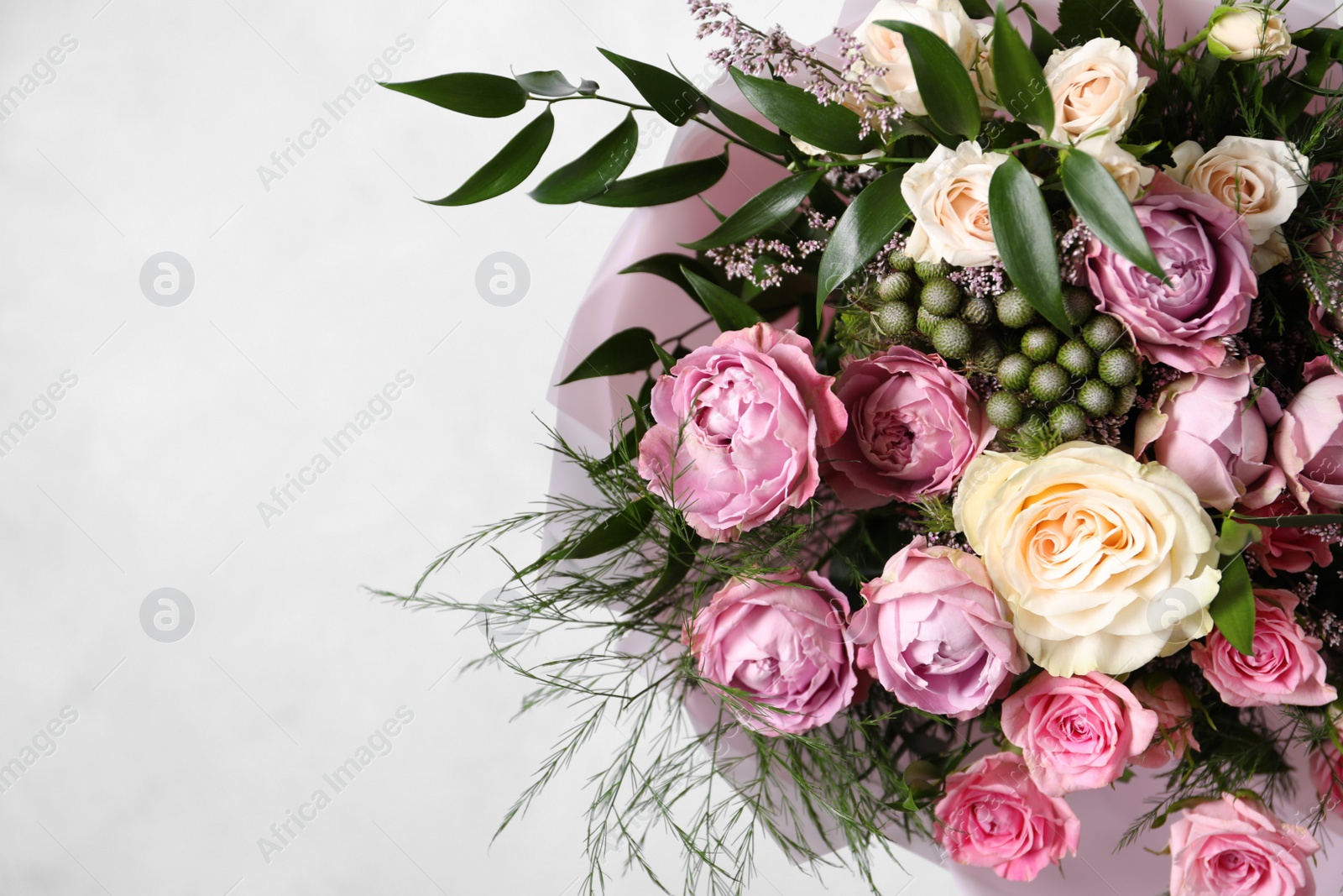 Photo of Beautiful bouquet with roses on light blue background, closeup