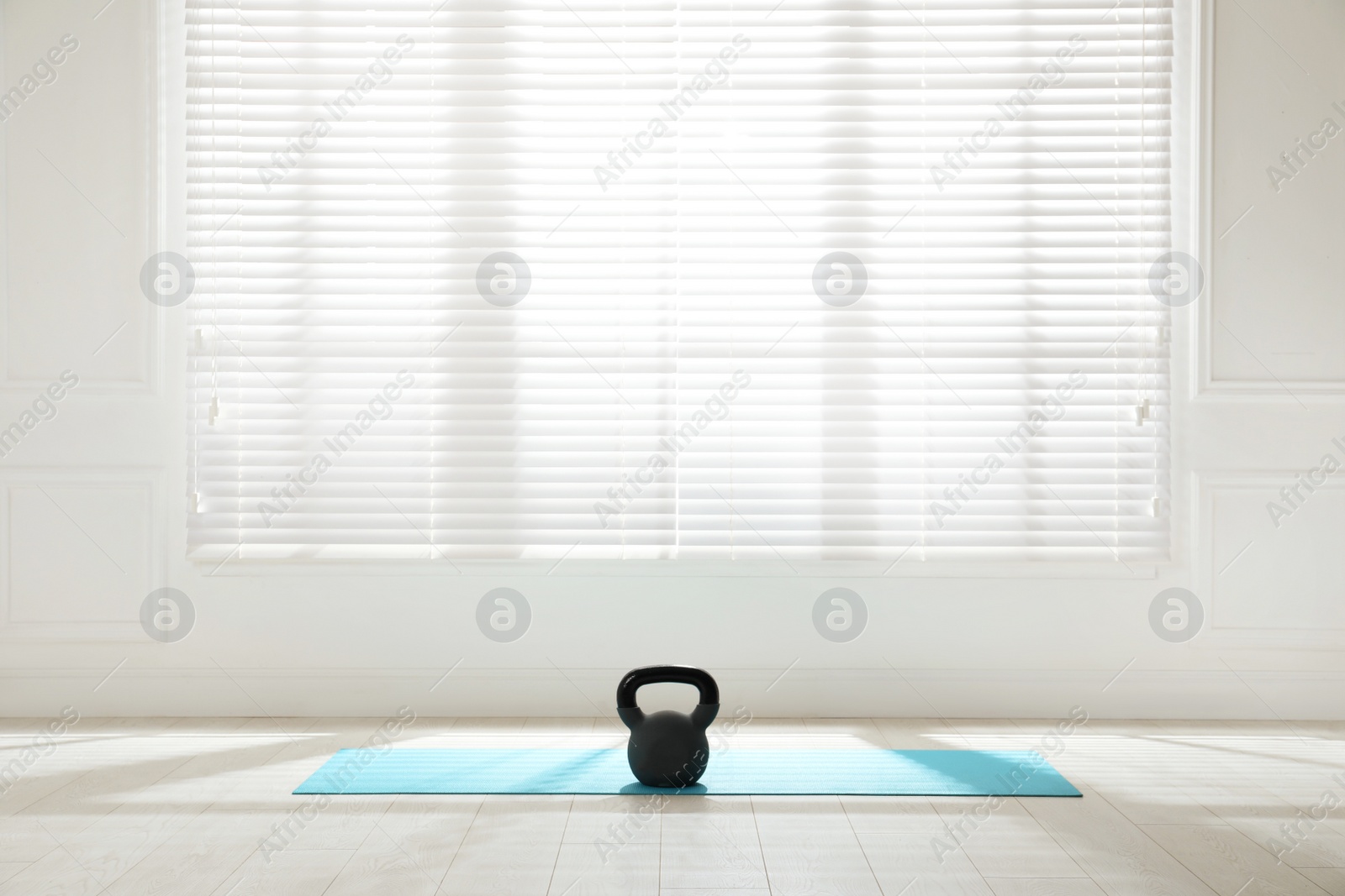 Photo of Exercise mat with kettlebell near window in spacious room