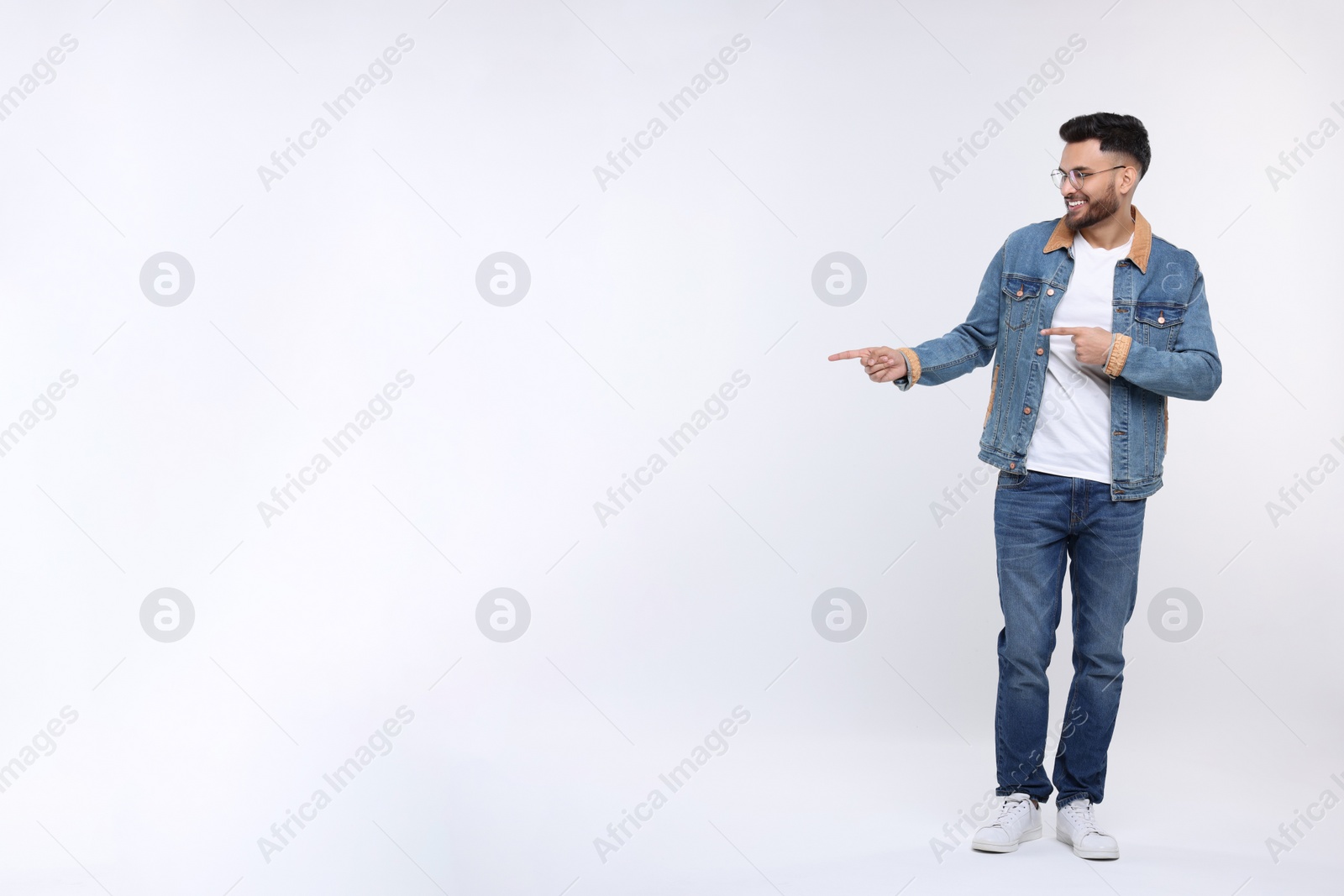 Photo of Happy young man pointing at something on white background, space for text