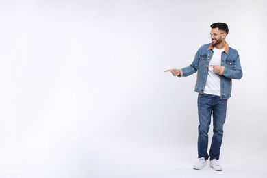 Happy young man pointing at something on white background, space for text