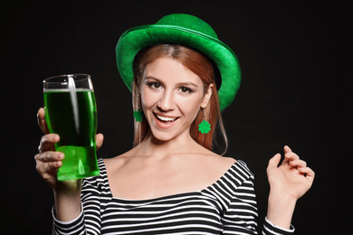 Young woman with green beer on black background. St. Patrick's Day celebration