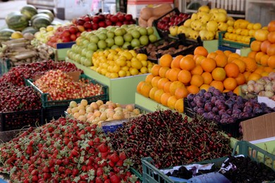 Many fruits and berries in crates selling outdoors