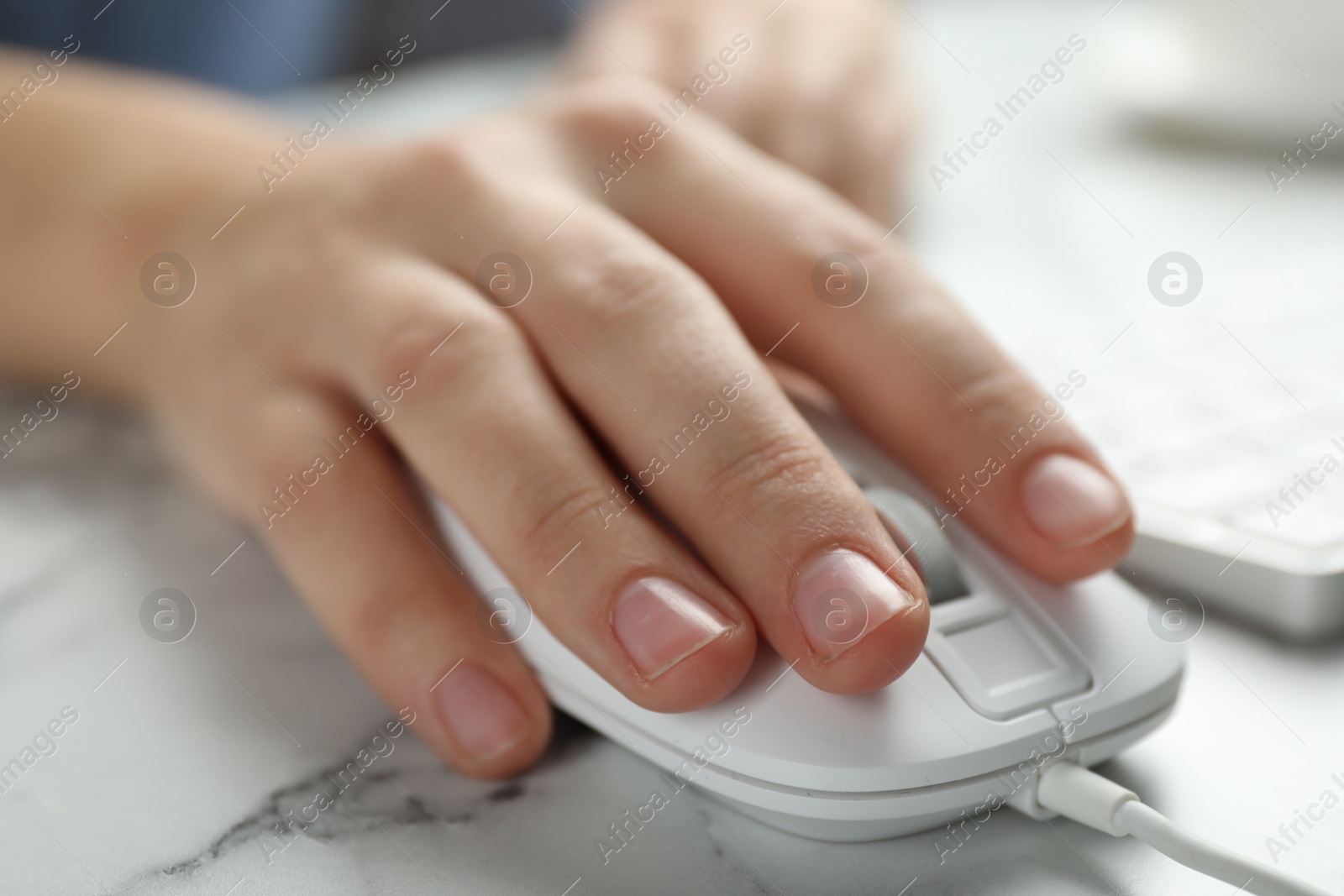 Photo of Woman using wired computer mouse at marble table, closeup