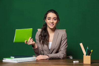 Photo of Portrait of beautiful young teacher sitting at table near chalkboard