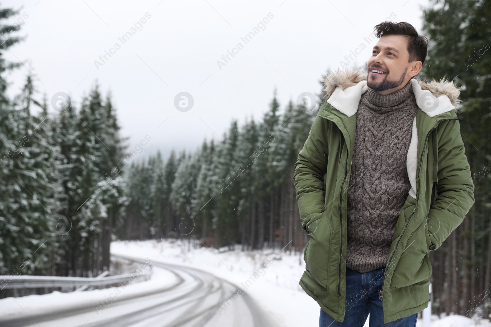 Photo of Man in warm clothes near snowy forest, space for text. Winter vacation