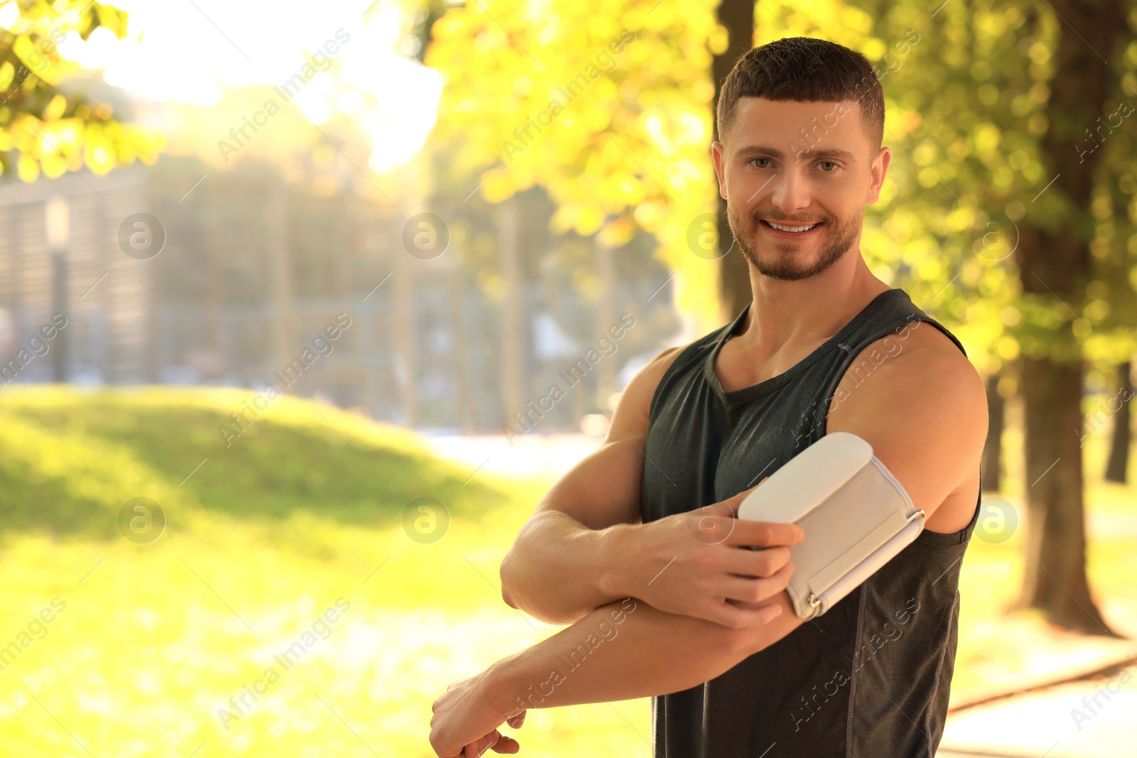 Photo of Attractive man checking blood pressure with modern monitor after training in park. Space for text