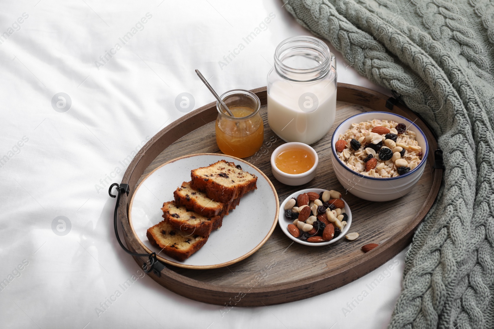 Photo of Tray with tasty breakfast on bed in morning