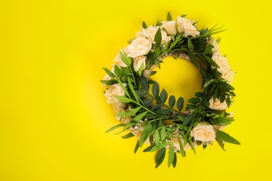 Photo of Wreath made of beautiful flowers on yellow background, top view. Space for text