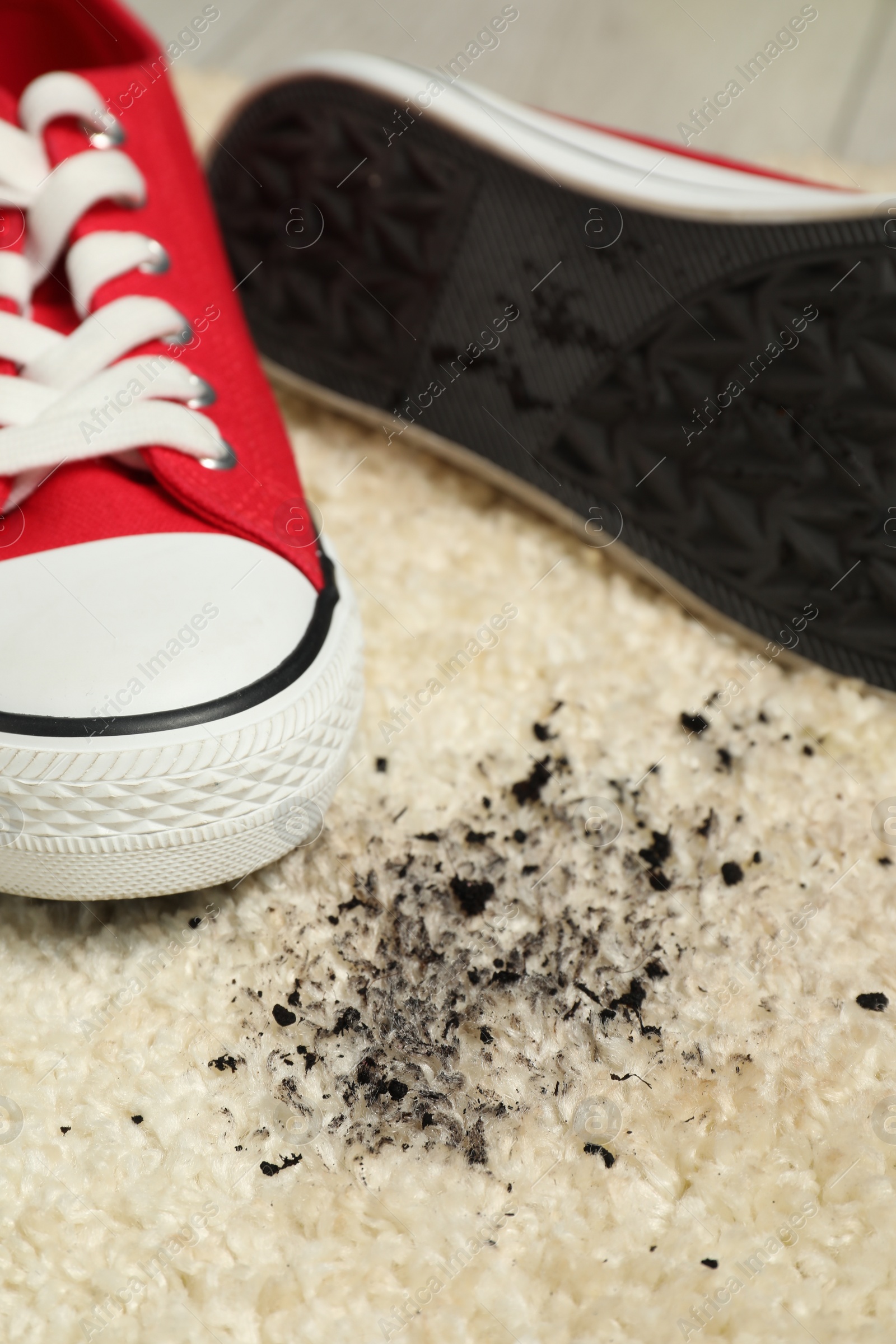 Photo of Red sneakers and mud on beige carpet, closeup