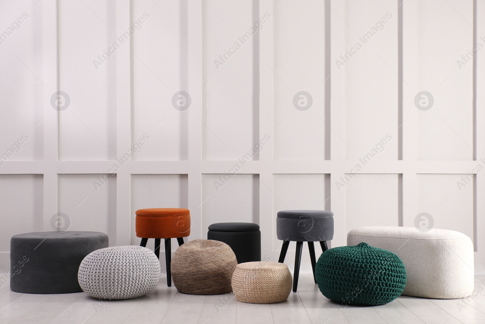 Photo of Different stylish poufs and ottomans near light wall