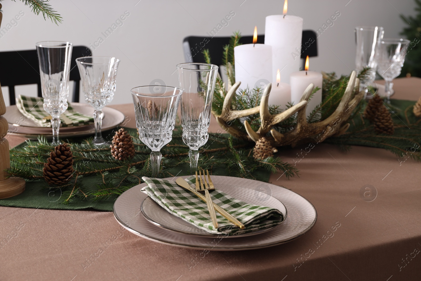 Photo of Christmas table setting with burning candles and other festive decor