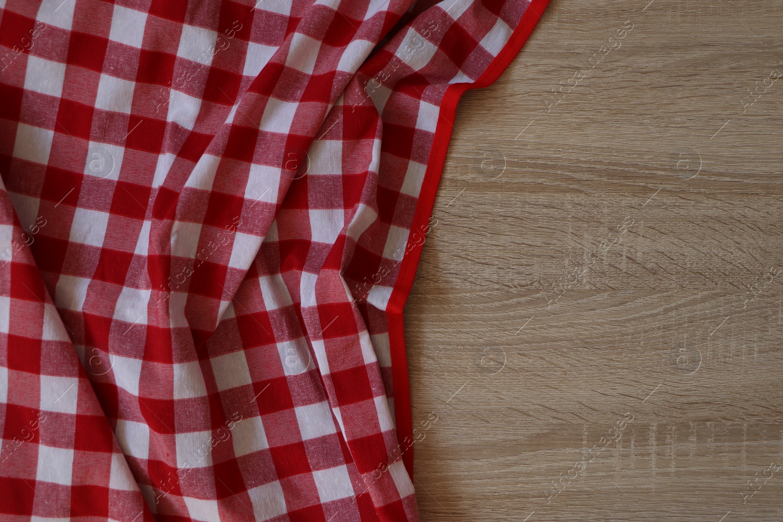 Photo of Checkered picnic cloth on wooden table, top view. Space for text