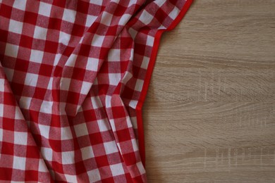 Photo of Checkered picnic cloth on wooden table, top view. Space for text