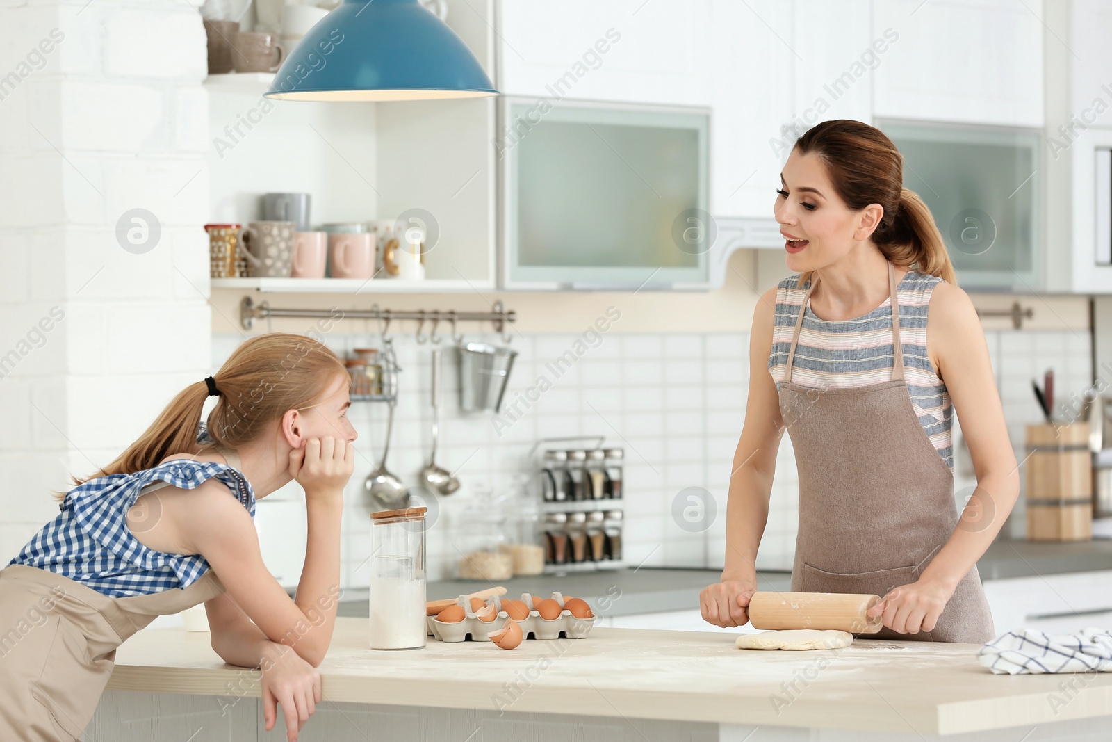 Photo of Mother and her daughter making dough at table in kitchen