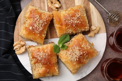 Photo of Eastern sweets. Pieces of tasty baklava and tea on brown table, flat lay