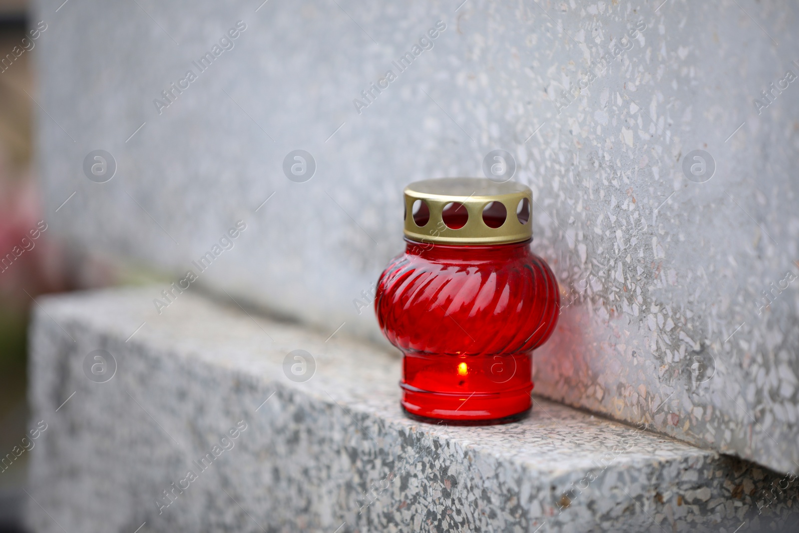 Photo of Candle on light grey granite tombstone outdoors. Funeral ceremony