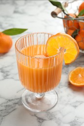 Photo of Delicious tangerine liqueur in glass and fresh fruits on white marble table, closeup