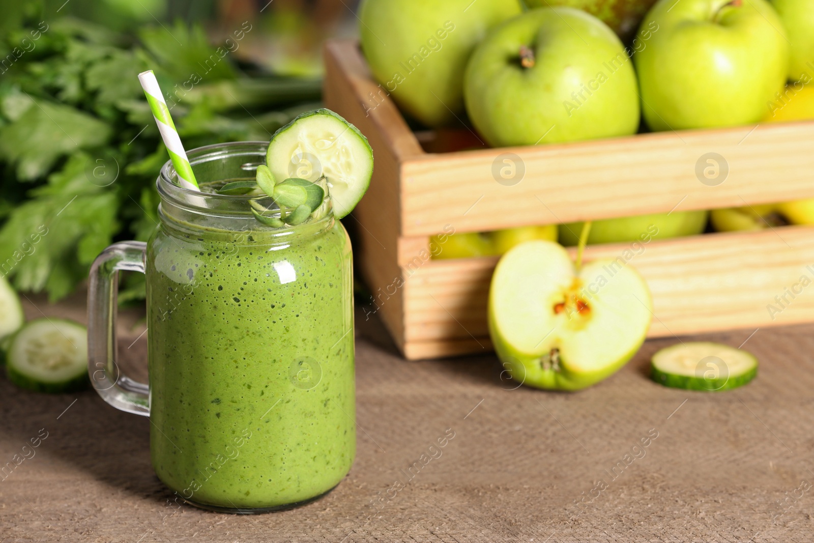 Photo of Mason jar of fresh green smoothie and ingredients on wooden table, space for text