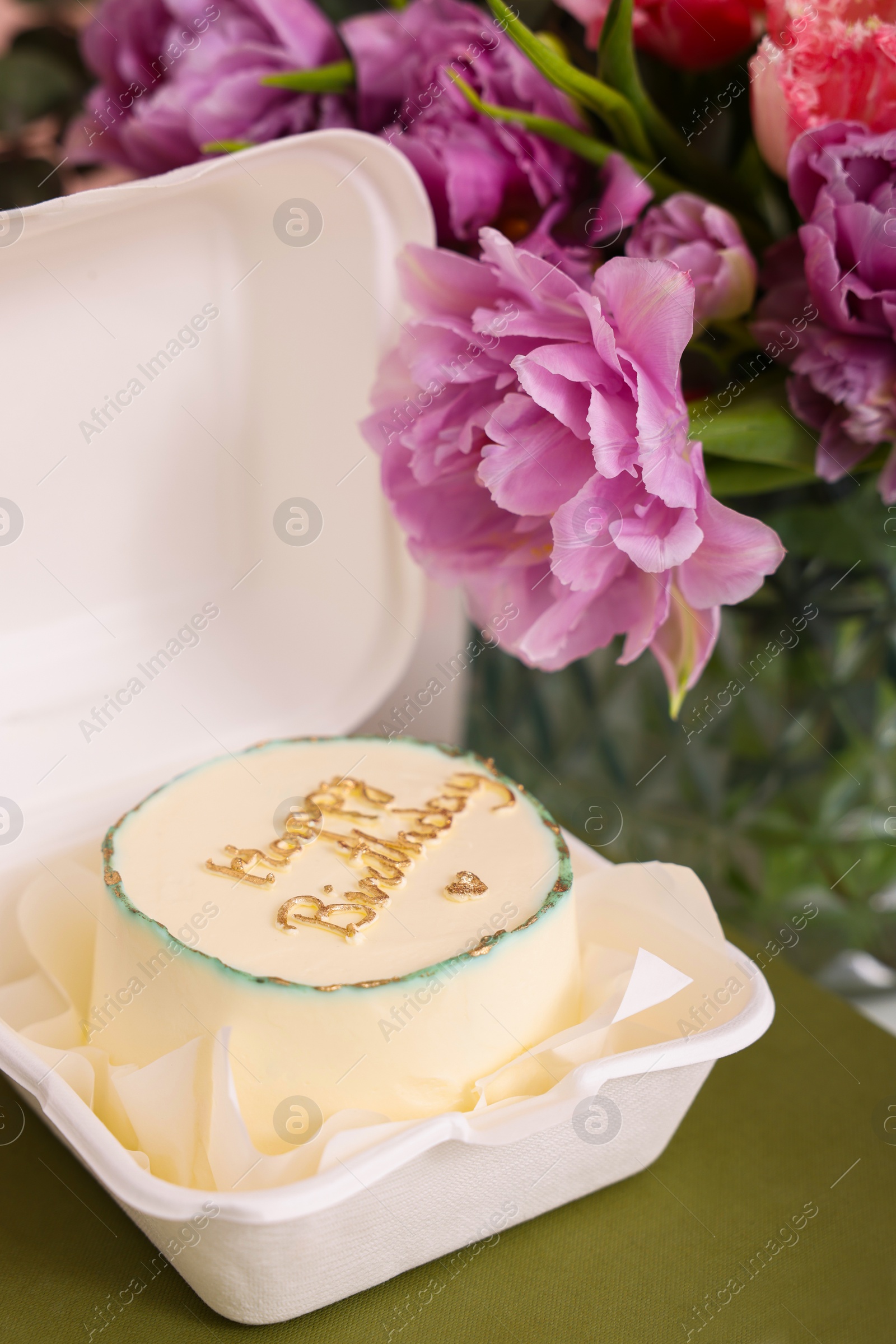 Photo of Delicious decorated Birthday cake and beautiful flowers on table indoors, closeup