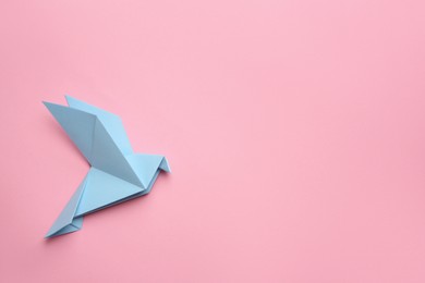 Photo of Beautiful light blue origami bird on pink background, top view. Space for text