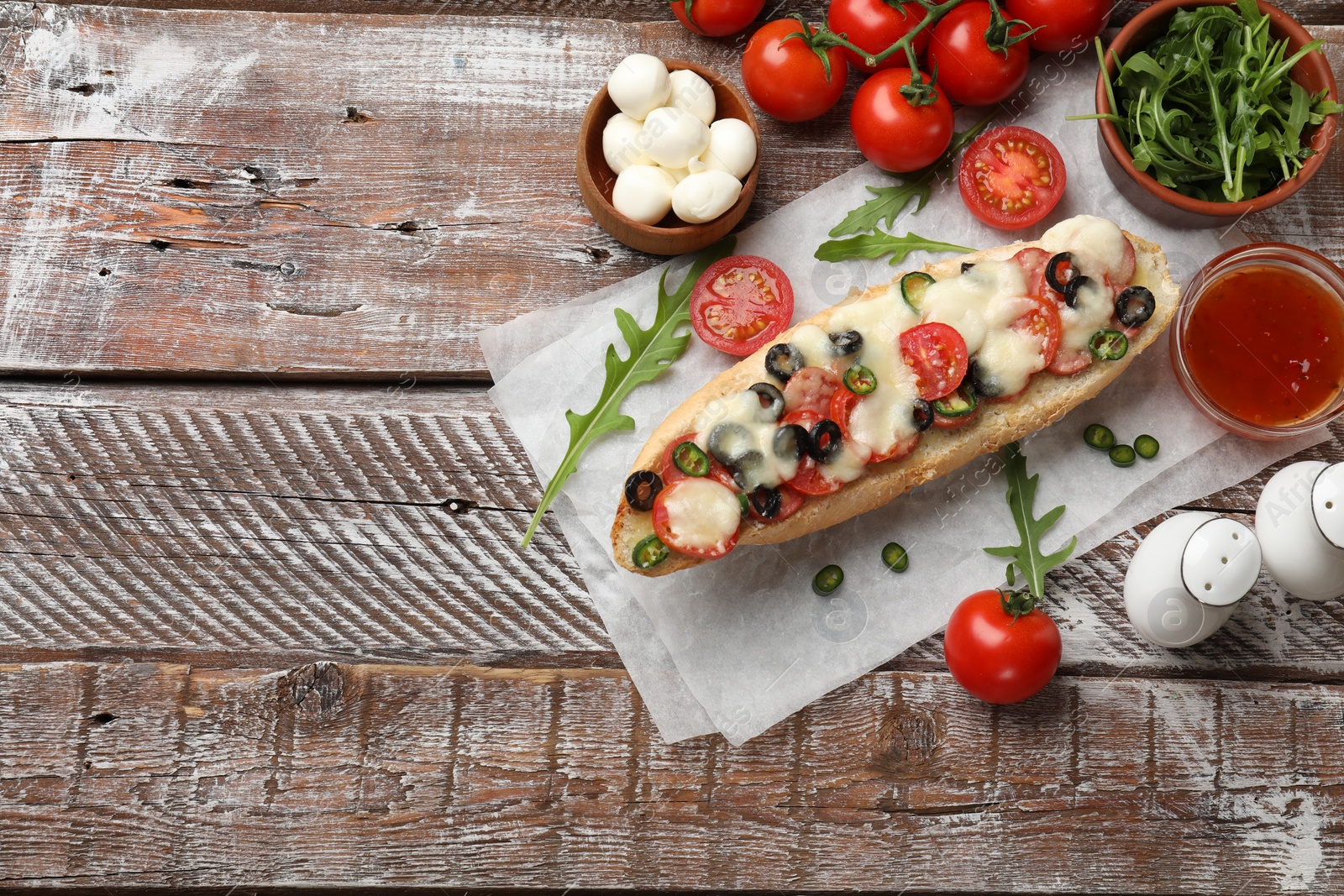 Photo of Tasty pizza toast and ingredients on wooden table, top view. Space for text