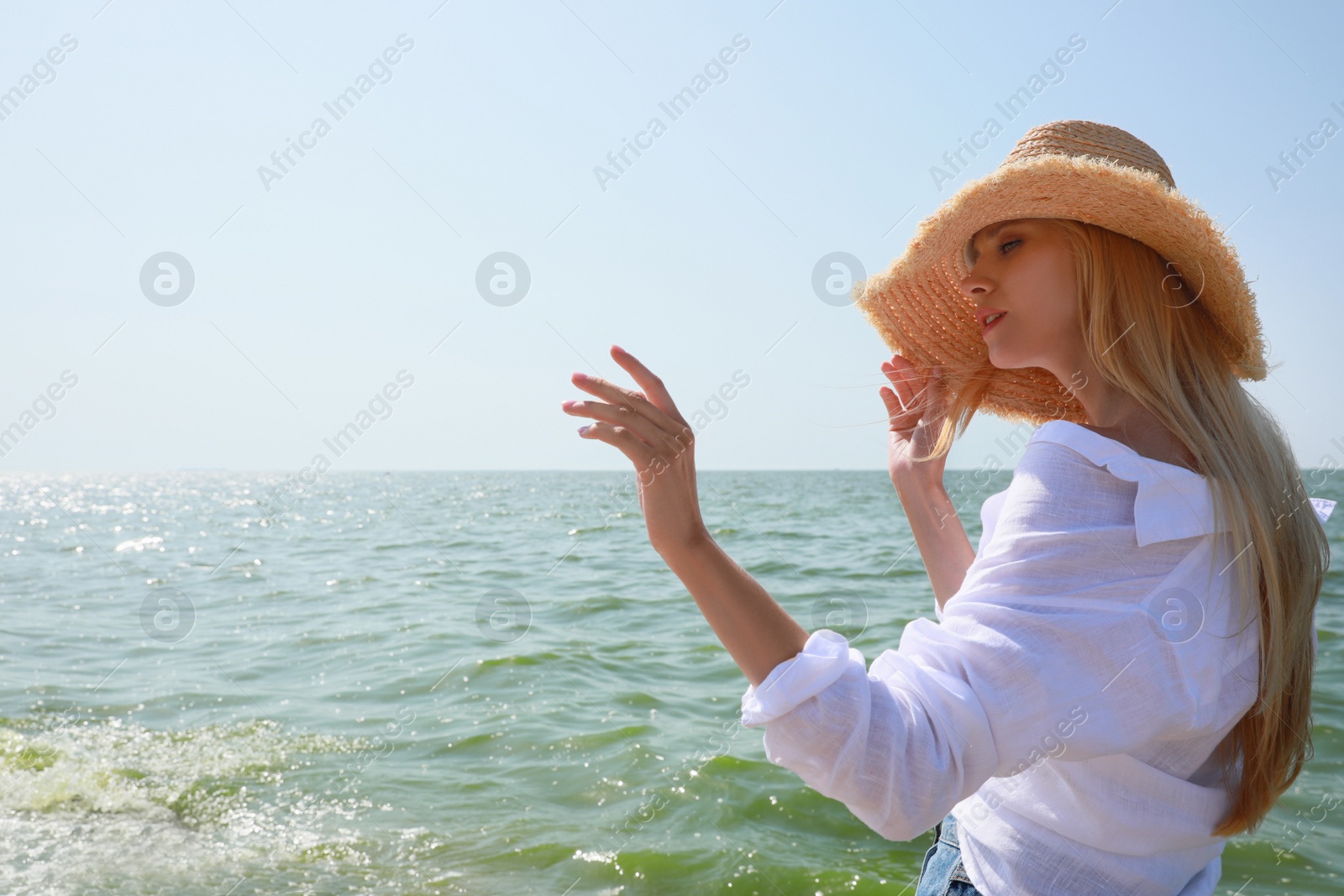 Photo of Beautiful young woman with straw hat near sea on sunny day in summer