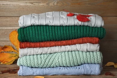 Photo of Stack of sweaters on wooden background. Autumn clothes