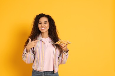 African American woman with French fries on yellow background, space for text