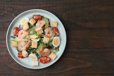 Delicious Caesar salad with shrimps on wooden table, top view. Space for text