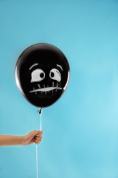 Photo of Woman holding spooky balloon for Halloween party on blue background