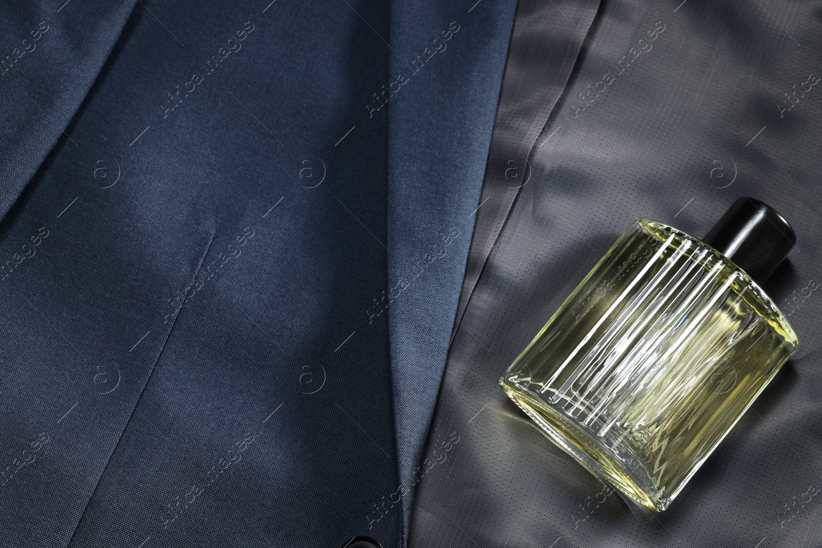 Photo of Luxury men's perfume in bottle on grey jacket, above view. Space for text