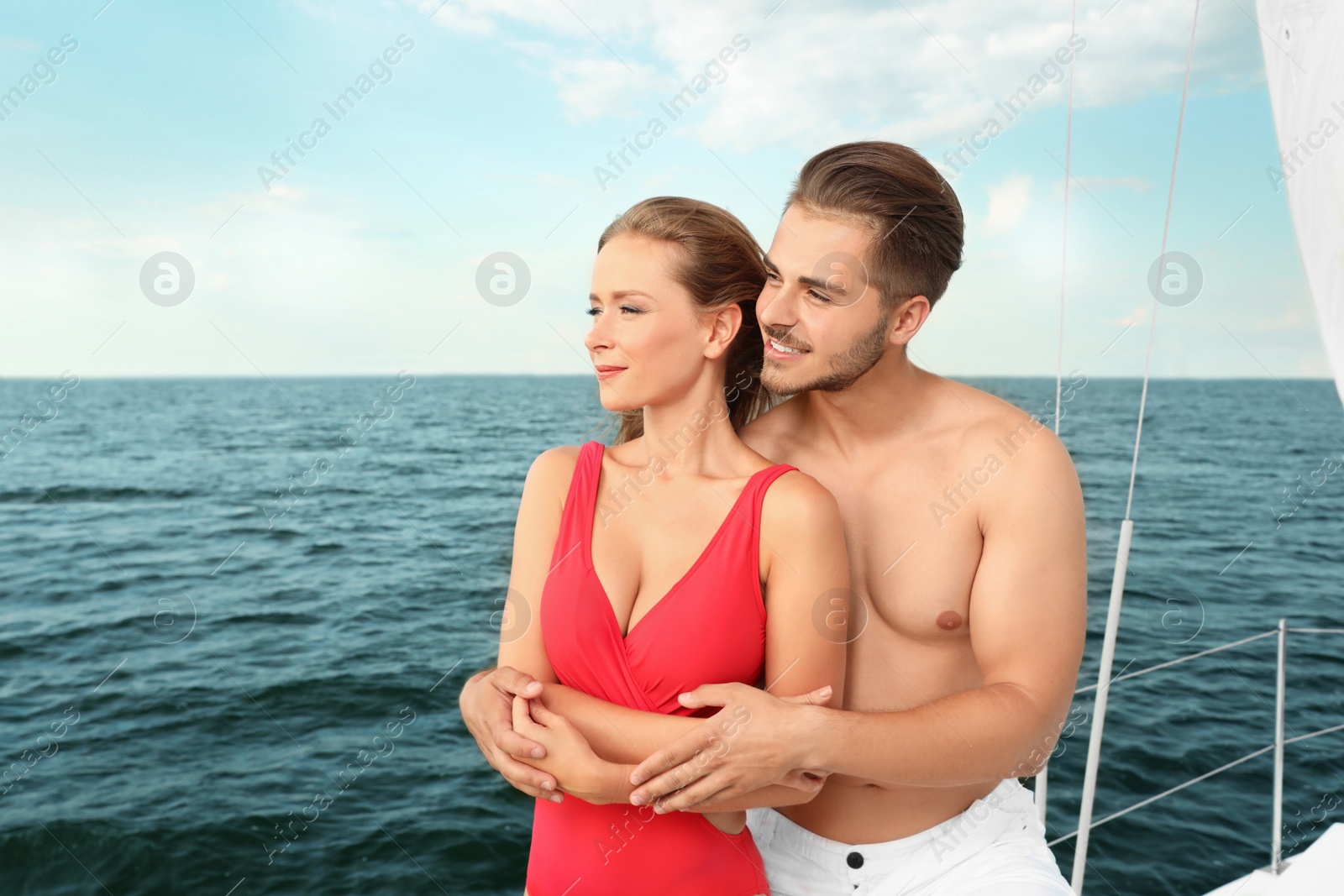 Photo of Young man and his beautiful girlfriend in bikini on yacht. Happy couple on vacation