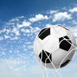 Soccer ball in net against blue sky