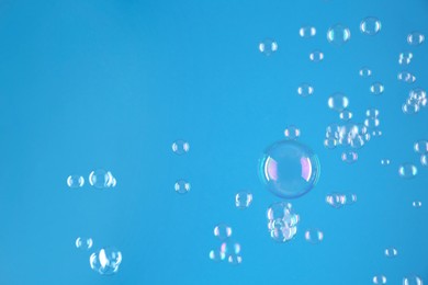 Beautiful transparent soap bubbles on light blue background