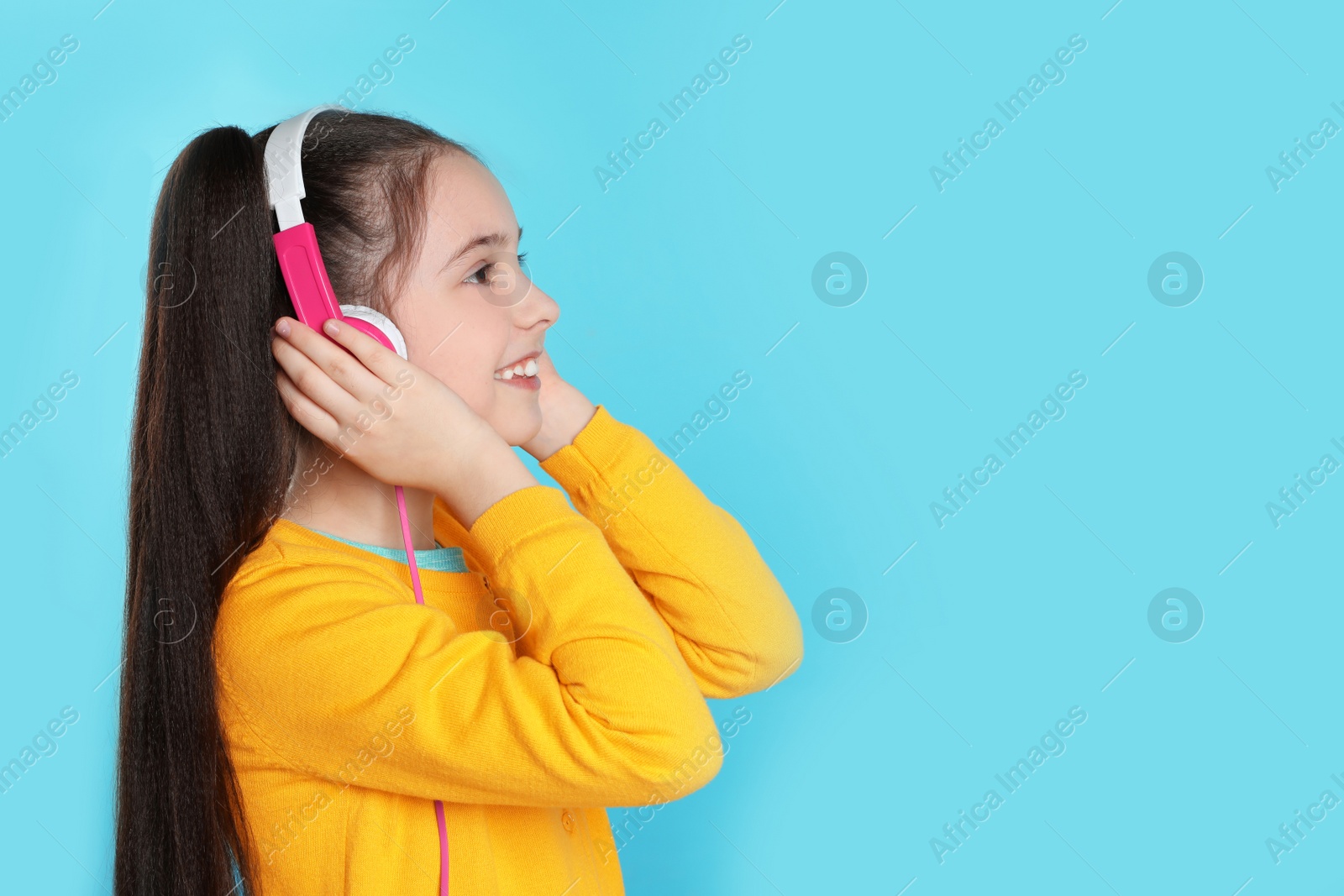 Photo of Cute girl enjoying music in headphones on color background. Space for text