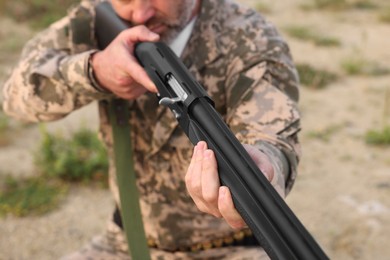 Photo of Man wearing camouflage and aiming with hunting rifle outdoors, closeup