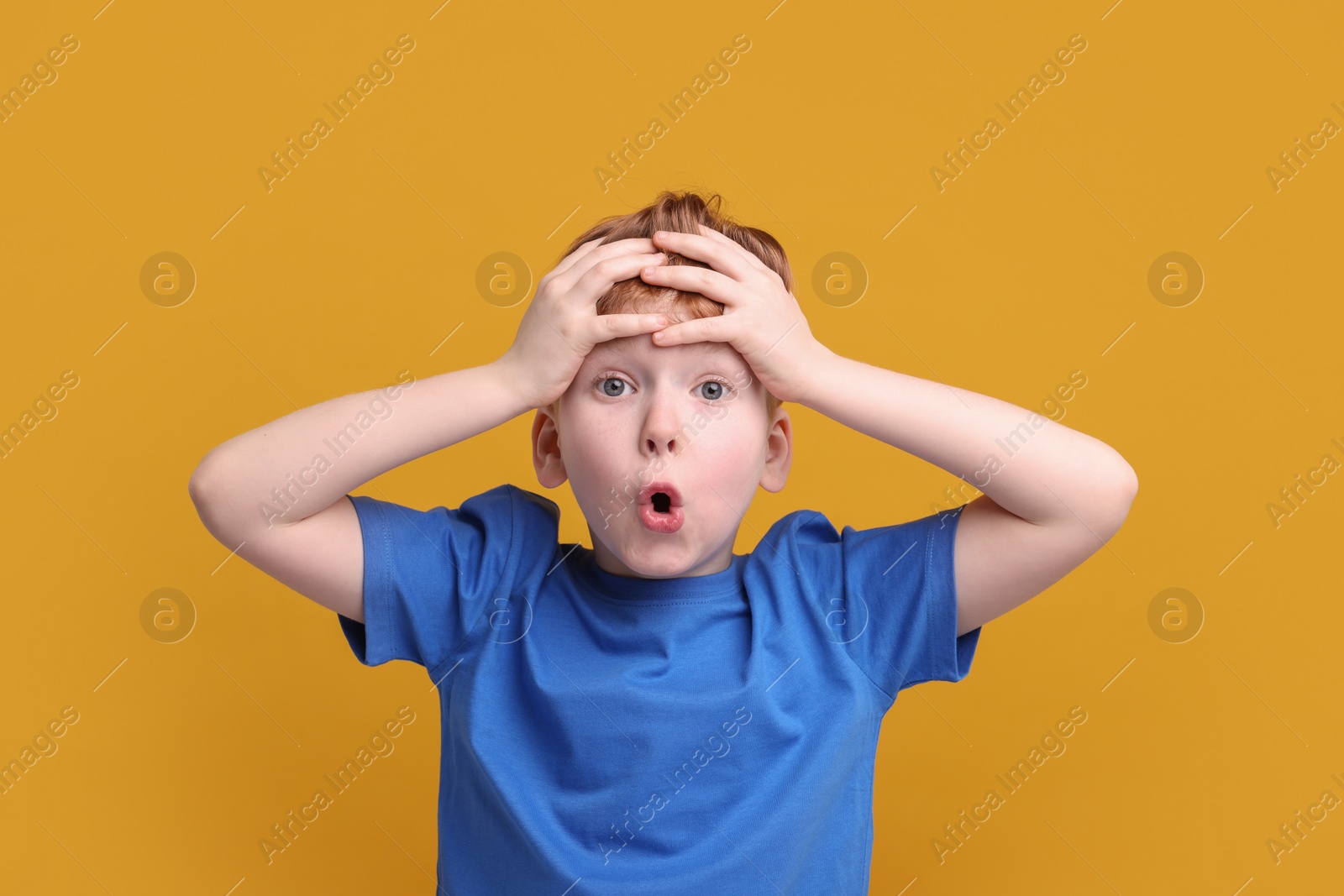 Photo of Portrait of surprised little boy on orange background