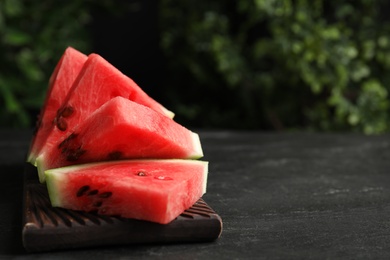 Photo of Slices of ripe juicy watermelon on black table, closeup. Space for text